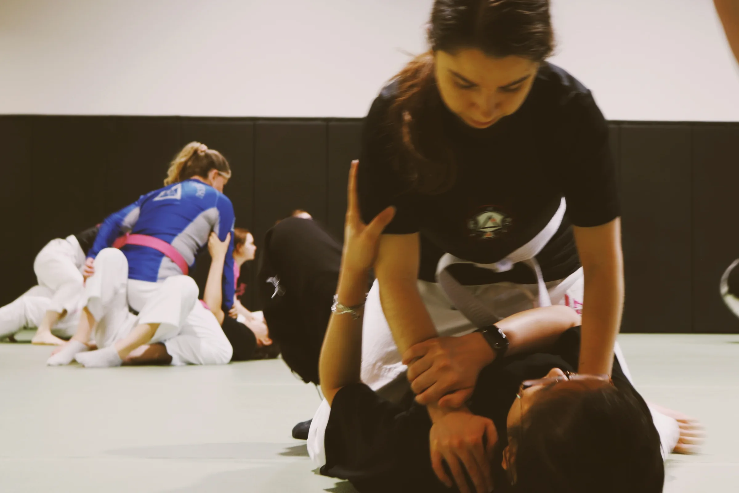 A student in a black-belt rashguard controlling a training partner on the mat.