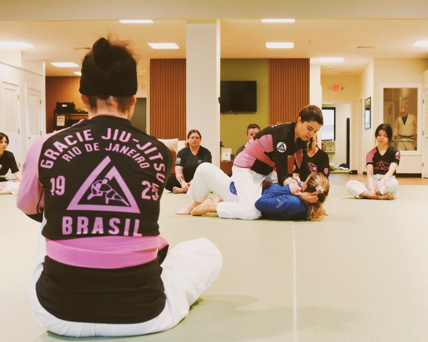 An instructor working one-on-one with a student on the mat.
