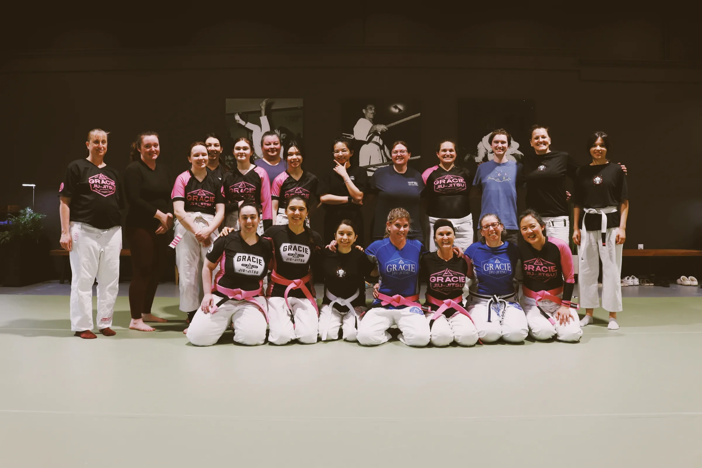 A group of women from the Women Empowered program standing and kneeling together on the mat.